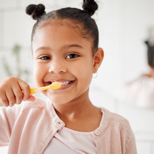 Young girl in pink shirt brushing her teeth