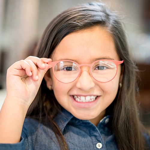 Smiling little girl in glasses after tooth extraction