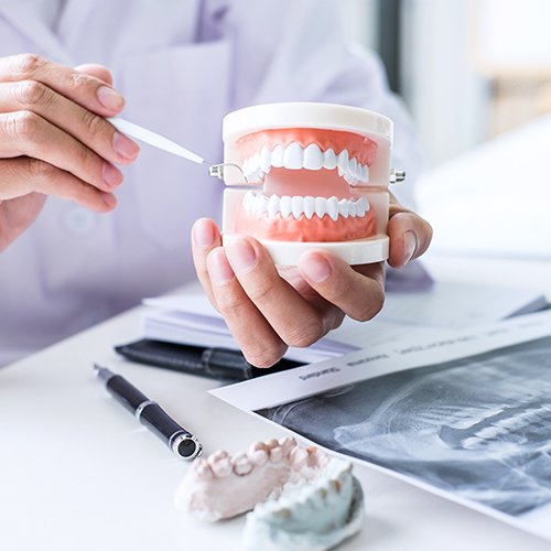 Dentist pointing to healthy smile model