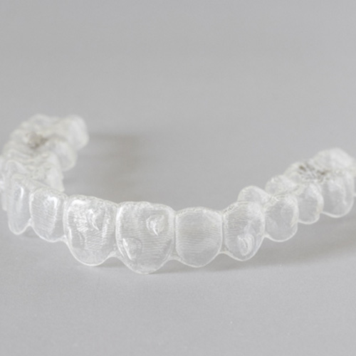 Invisalign clear aligner lying on grey surface