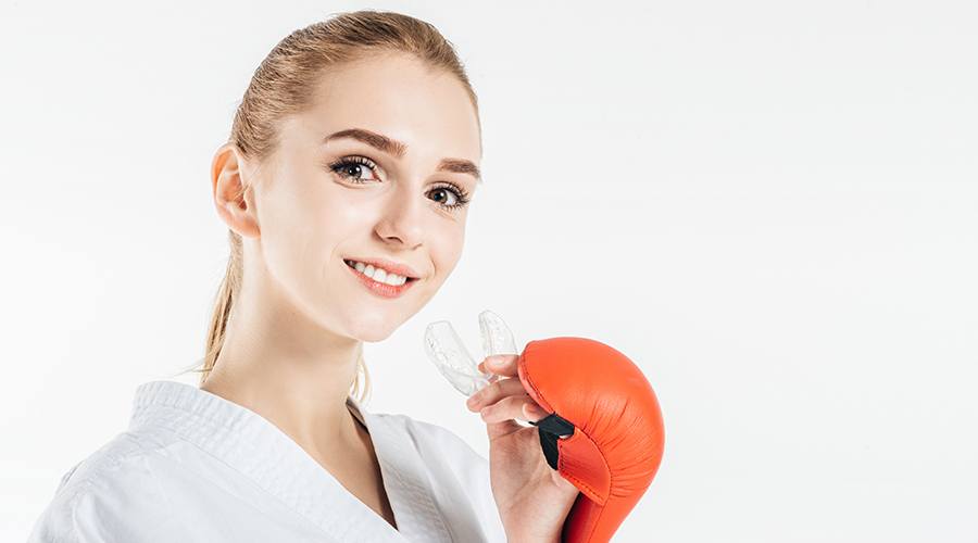 Young woman with boxing gloves placing her athletic mouthguard