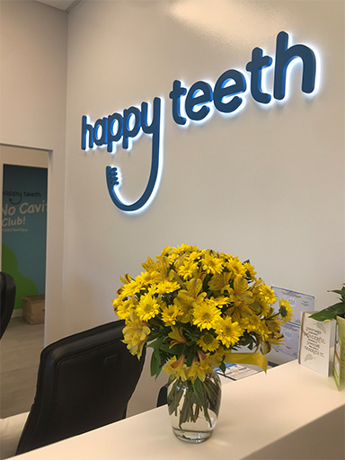Happy Teeth sign over dental office reception desk