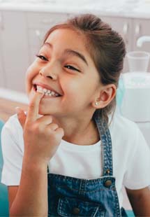 Child smiling in mirror after getting metal-free filling