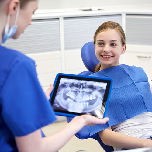 Little girl smiling as team member review digital dental x-rays