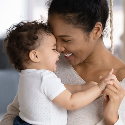 A mother holding and smiling at her baby