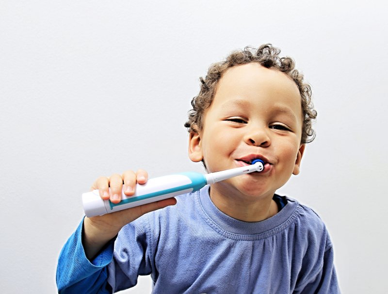 little boy using electric toothbrush