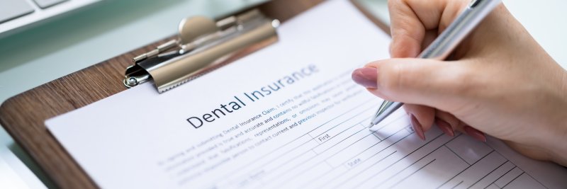 Filling out a dental insurance form on a clipboard