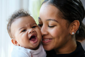 Happy mother smiling and holding a laughing baby 