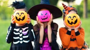 Three kids holding pumpkins over their faces