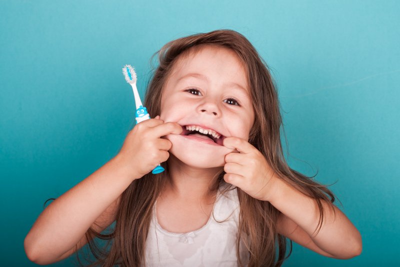 Child makes silly face while holding toothbrush