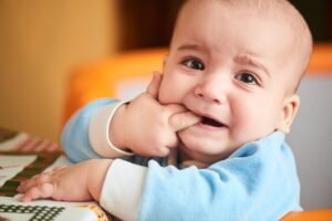Anxious looking baby with finger in their mouth.